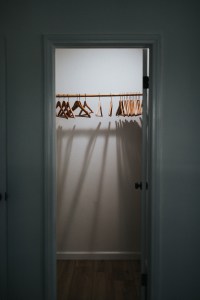 Empty closet with open door and wood clothes hangers.